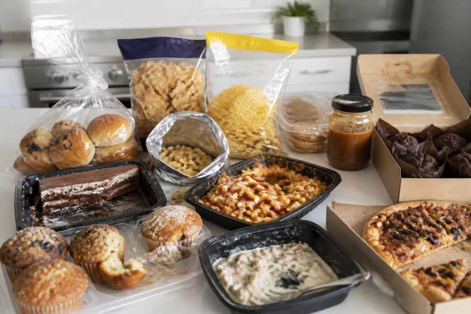 A kitchen counter displaying various unappealing and opened packaged foods from Costco in a modern kitchen setting.