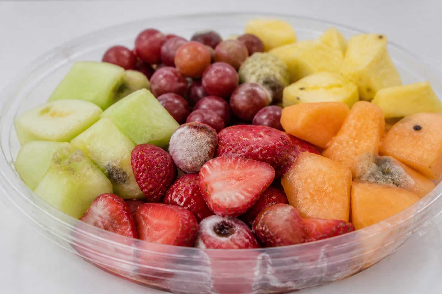 A pre-made fruit platter with various sliced fruits showing signs of mold and spoilage.