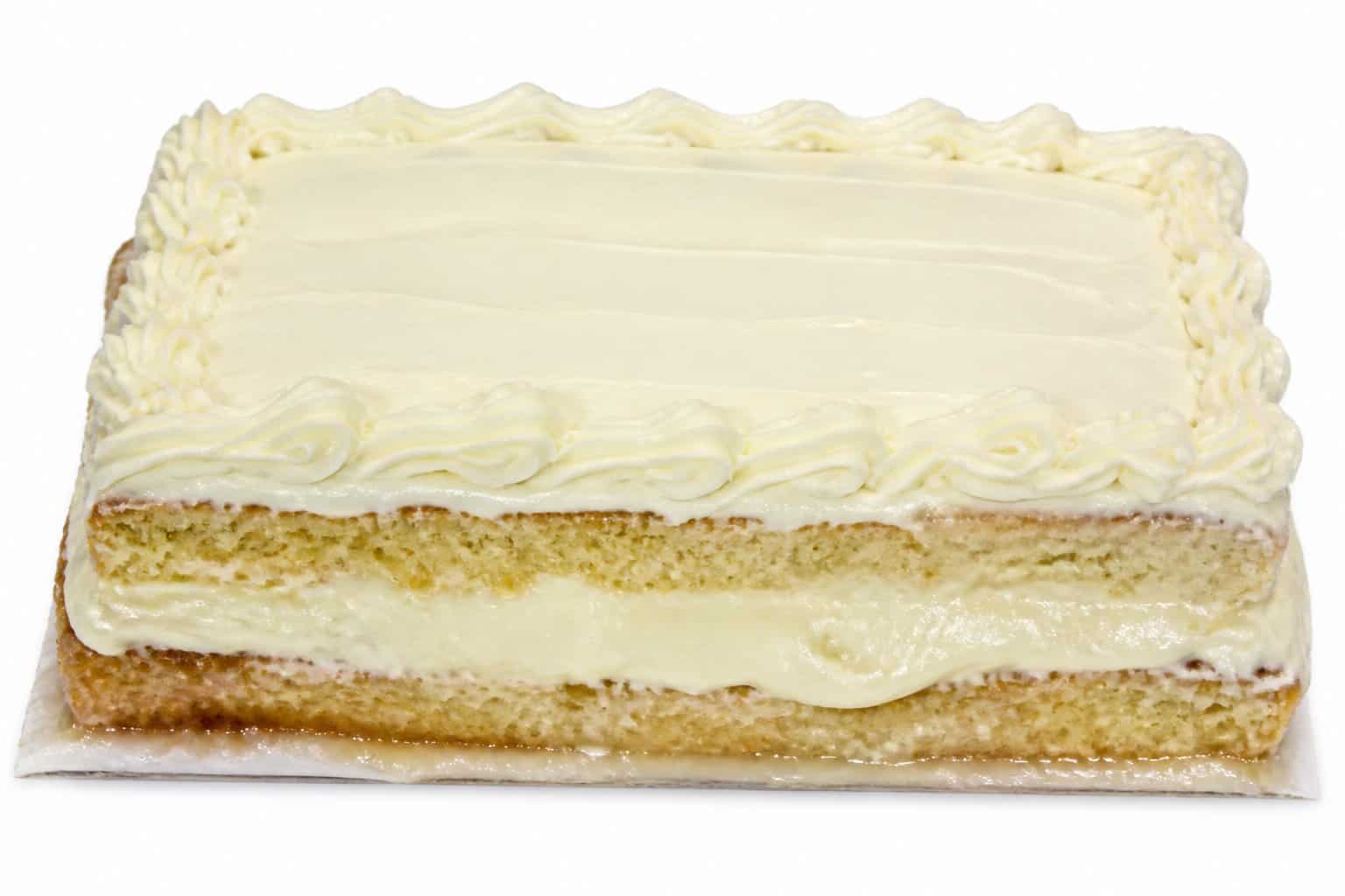 A close-up of a rectangular sheet cake with thick frosting that looks moist and slightly soggy on a plain background.