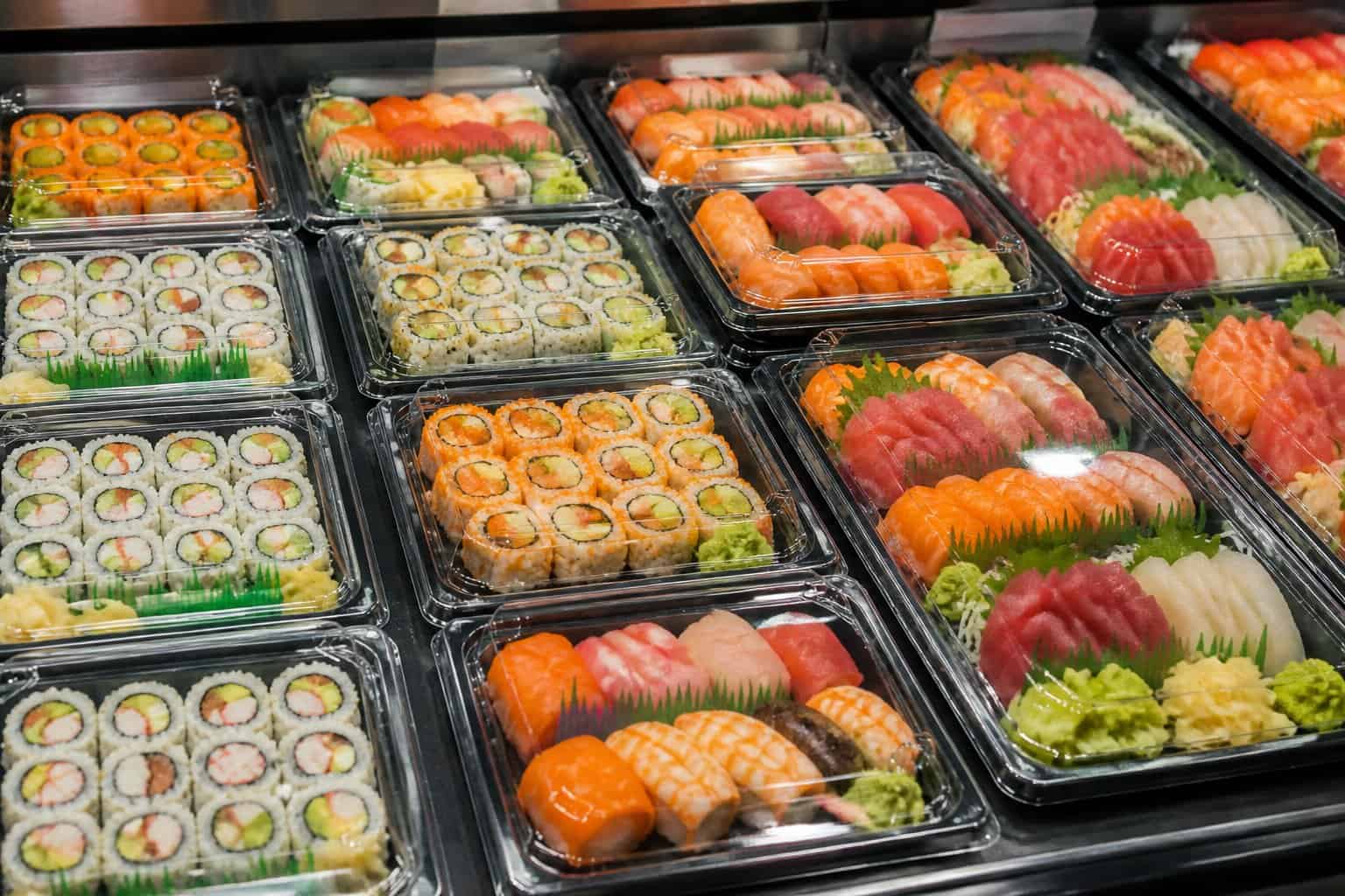 Pre-packaged sushi trays displayed on a refrigerated supermarket shelf.