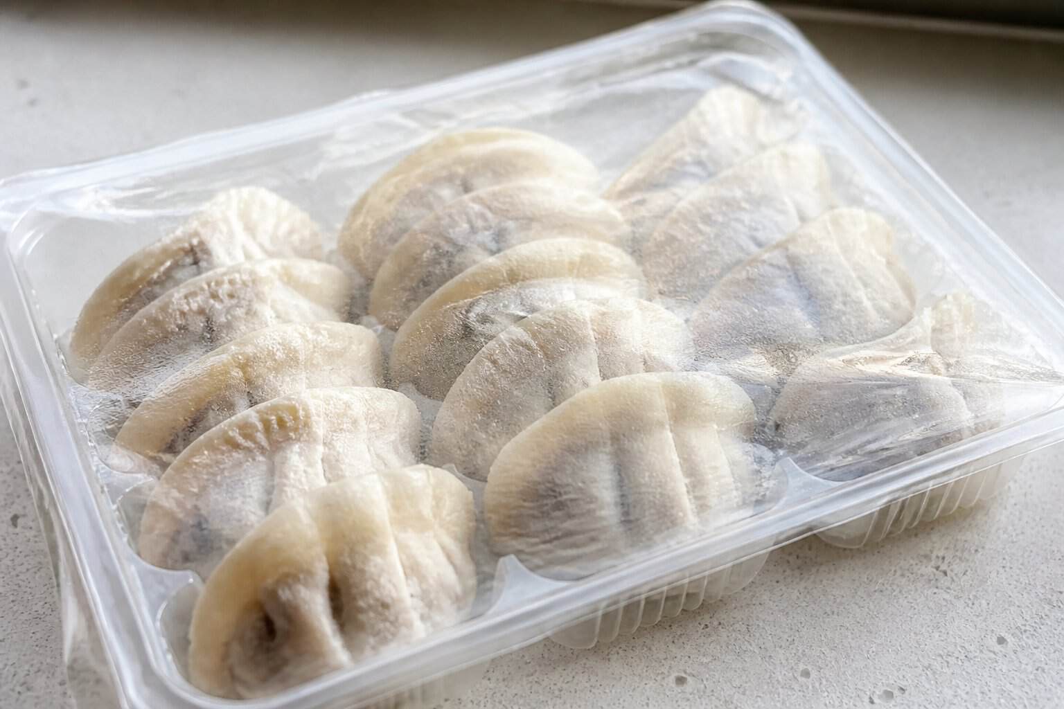 A package of frozen dumplings with a textured, gummy-like wrapper on a kitchen countertop.
