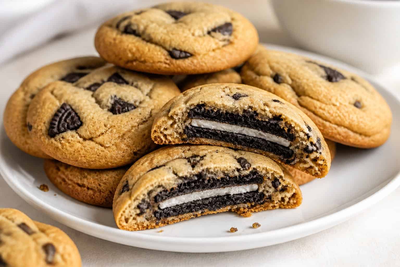 A plate of golden cookies, including one cut open to show an Oreo cookie baked inside.