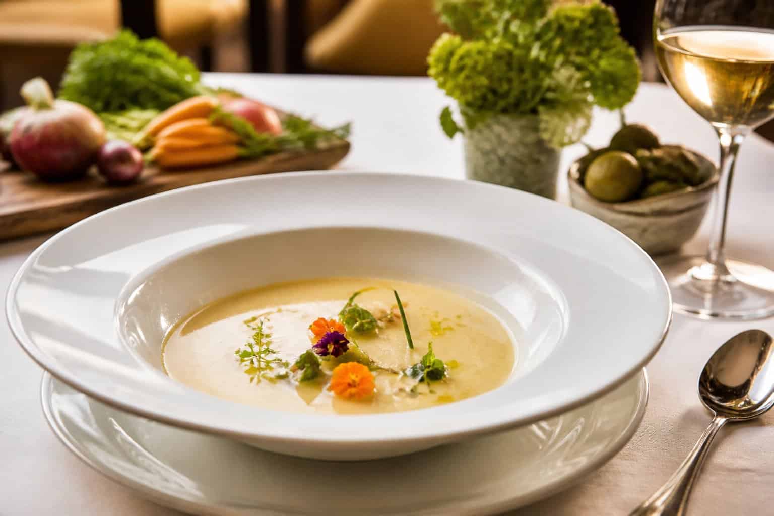 An elegant bowl of garnished soup on a table in an upscale restaurant.