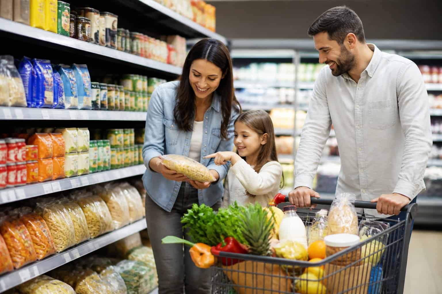 A parent and child selecting affordable groceries in a supermarket aisle.