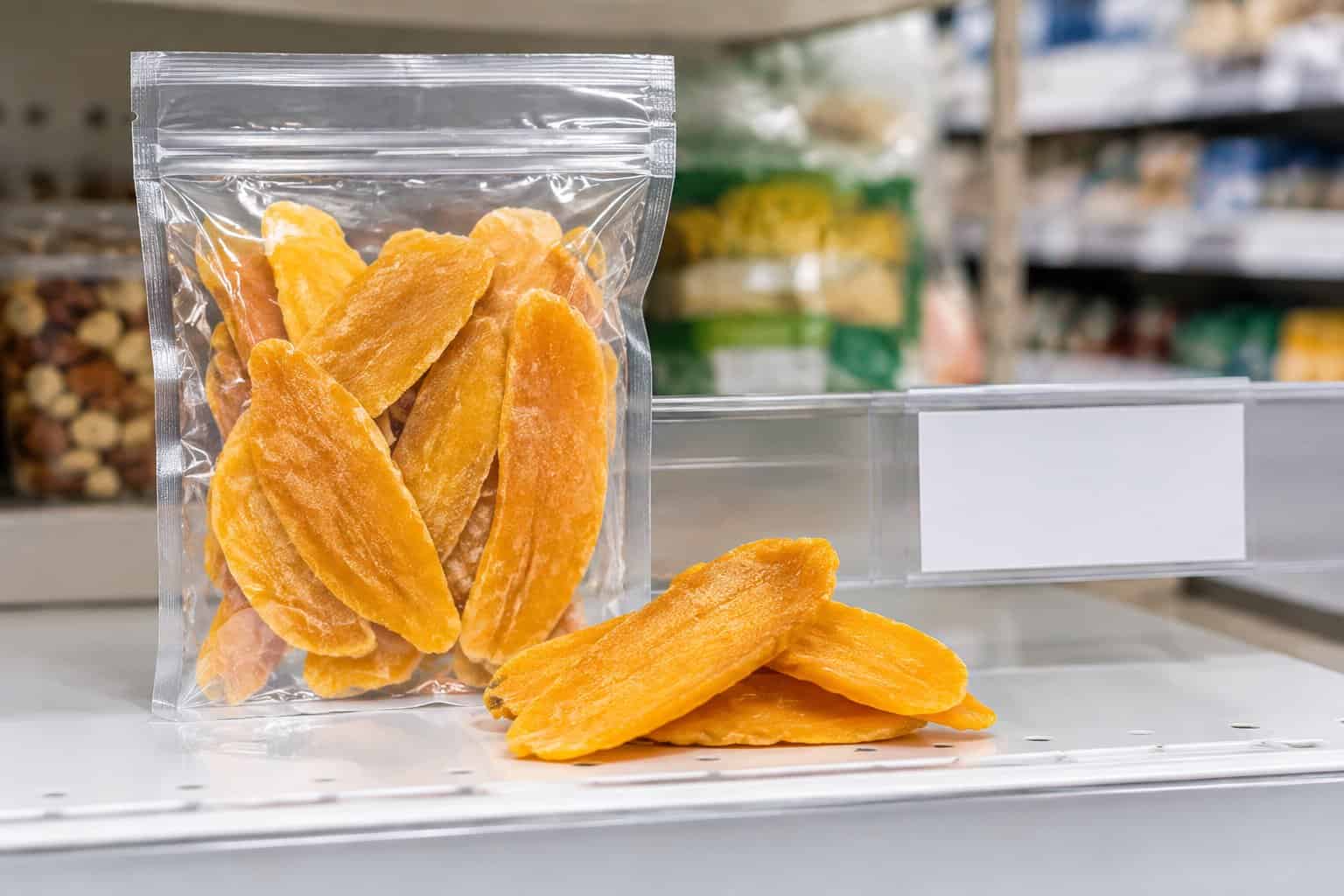 A bag of dried mango slices beside a price tag on a grocery shelf.