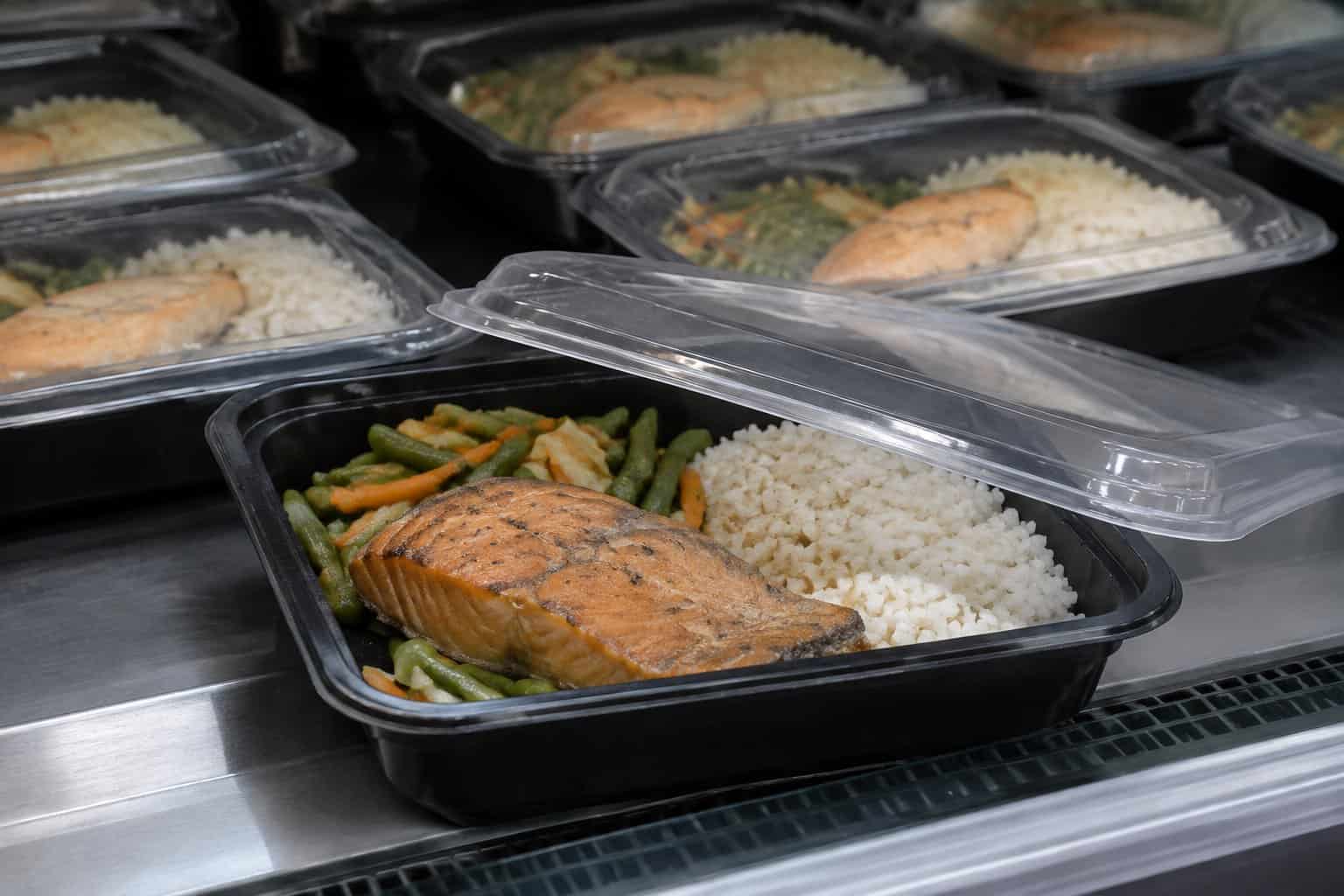 Several prepared salmon meals sit in a refrigerated display case.