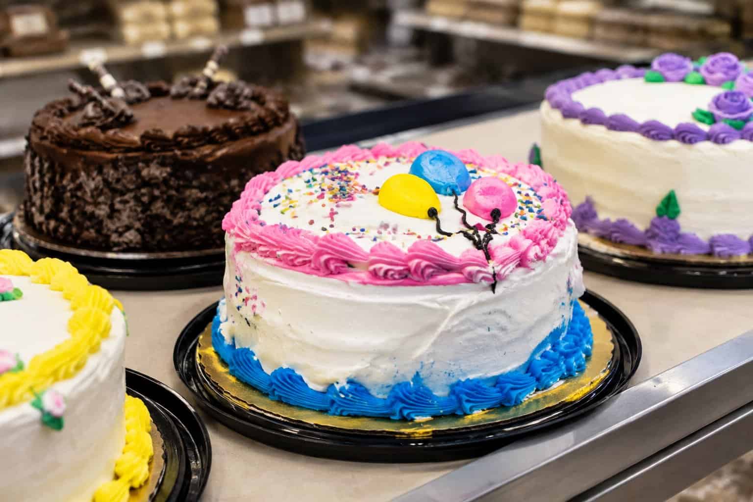 Several decorated cakes sit on a bakery counter.